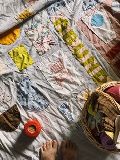 someone's feet are on the bed next to a quilt and some yarns