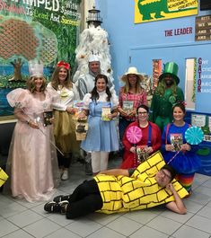 a group of people dressed up in costumes posing for a photo with one man laying on the ground