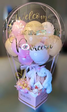 a bunch of balloons in a box with the words welcome written on it and some stuffed animals inside