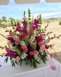 a vase filled with lots of pink and white flowers sitting on top of a table