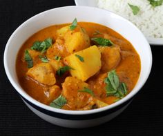 there is a bowl of curry and rice next to the plate with rice on it