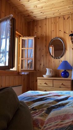 a bedroom with wood paneling and a bed next to a mirror on the wall