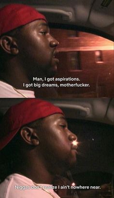 a man sitting in the back seat of a car next to another man wearing a red hat