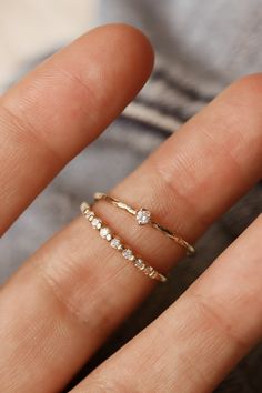 a woman's hand with two gold rings on top of her finger and one in the middle