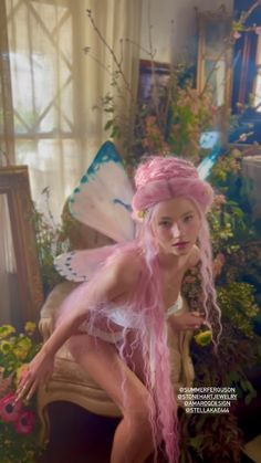 a woman with pink hair is dressed as a fairy