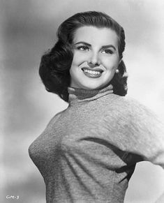 an old black and white photo of a woman with her hands on her hips, smiling