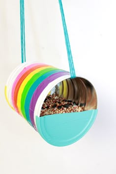 a colorful bird feeder hanging from a string with birdseed in the bottom and inside