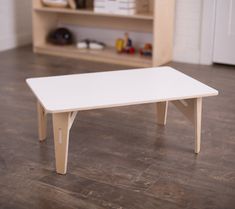 a white table sitting on top of a hard wood floor next to a book shelf