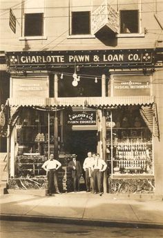 two men are standing in front of a pawn and loan store on the corner of a city street