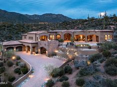 an aerial view of a home in the desert at night with lights on and landscaping