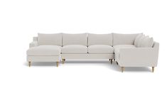 a white sectional couch sitting on top of a white floor next to a wooden leg chair