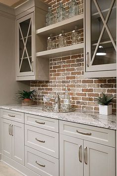 a kitchen with white cabinets and brick wall