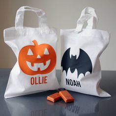 two bags with halloween designs on them sitting next to one another and some chocolates