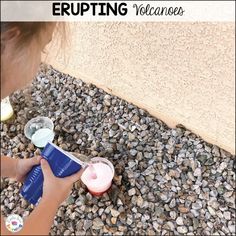 a young child using an electric hand held sprayer to paint rocks on the ground