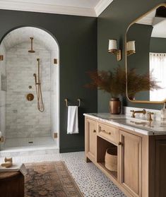 a bathroom with green walls and marble counter tops, gold fixtures and an oval mirror