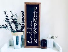 a wooden sign sitting on top of a white shelf next to a potted plant