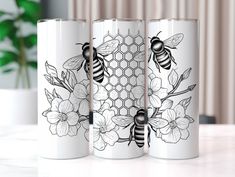 two white coffee mugs with bees and flowers on them