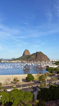 boats are docked in the water near a beach and mountains with blue sky above them