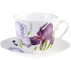 a cup and saucer with purple flowers painted on the side, sitting next to each other