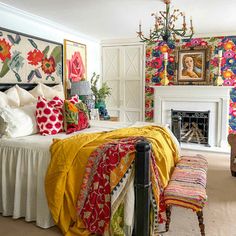 a bedroom decorated in bright colors with a fireplace and wall hangings above the bed