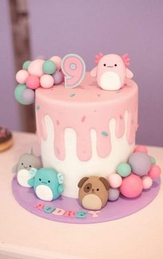 there is a pink cake with animals on it