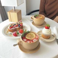 three desserts are sitting on plates on a white tablecloth with a man in the background