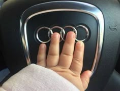 someone is holding their hand on the center console of a car with three rings in it