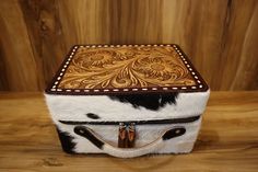 a cowhide and leather box sitting on top of a wooden table