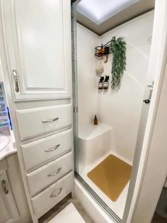 a bathroom with white cabinets and a glass shower door that has gold flooring in it