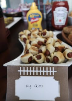 there are many small pigs in a blanket on the table with other snacks and condiments