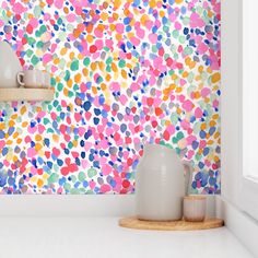 the wall is decorated with multicolored polka dot paper and vases in front of it