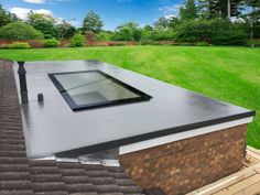 a flat roof with a skylight on top of it in the middle of a yard