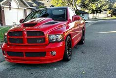 a red truck is parked on the side of the road in front of some houses