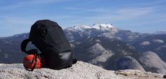 a backpack sitting on top of a rock with mountains in the background