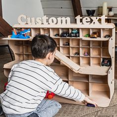 a young boy playing with toys in front of a wooden sign that says custom text