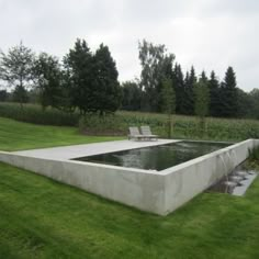 an image of a concrete pool in the middle of a field with trees behind it