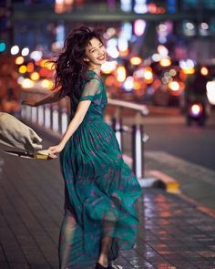 a woman in a green dress is walking down the street with her hand on her hip