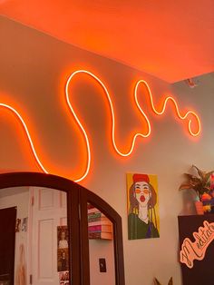 an orange neon sign hanging from the side of a wall next to a mirror and potted plant