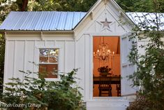 a small white house with a chandelier hanging from it's side window