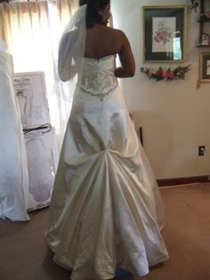 a woman in a wedding dress looking at herself in the mirror with her veil pulled back