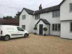 a white van is parked in front of a large house with black doors and windows