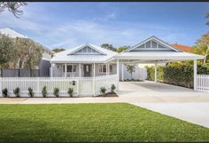 a white house with two cars parked in front of it and a fence around the yard