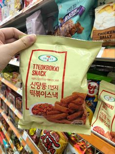 a person is holding up a bag of snack in a grocery store's aisle