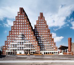 two tall brick buildings sitting next to each other in front of a blue cloudy sky