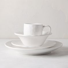 three white cups and saucers stacked on top of each other