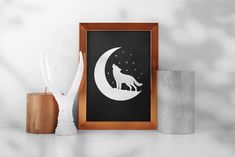 a white wolf standing on top of a moon next to two vases and a framed poster