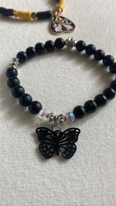 Introducing the ultimate accessory for all you dark and daring fashionistas out there - our black butterfly bead bracelet! With its goth-inspired, this piece is the perfect addition to any Halloween outfit or just an edgy everyday look.  Featuring intricate flower spacer beads and a breathtaking black butterfly charm, this beaded bracelet is sure to turn heads wherever you go.  Measuring 7 inches in width, it's the perfect fit for most wrists. So why wait? Add a touch of dark elegance to your wardrobe today with this new, edgy bracelet. Black Charm Bracelet, Adjustable Emo Style Bracelet As Gift, Adjustable Emo Style Bracelet For Gift, Adjustable Emo Style Bracelets, Black Edgy Bracelets As Gift, Alternative Style Black Bracelets As Gift, Alternative Style Black Bracelet Gift, Alternative Style Black Bracelet For Gift, Edgy Black Bracelet For Festivals