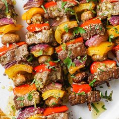 skewered meat and vegetables on a white plate with parsley sprinkled around them