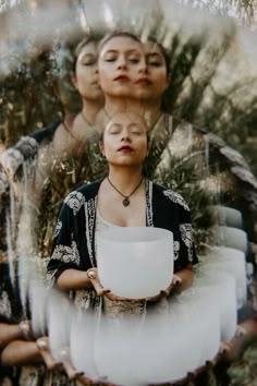 two women are standing in front of some trees and one is holding a white bowl