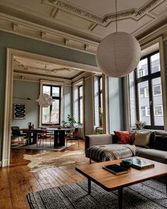 a living room filled with lots of furniture next to large windows on top of a hard wood floor